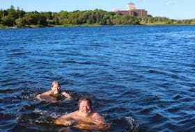 Jordan Young and Kathleen Parewick take an evening swim in Long Pond in St. John's, with the Confederation Building in the background.