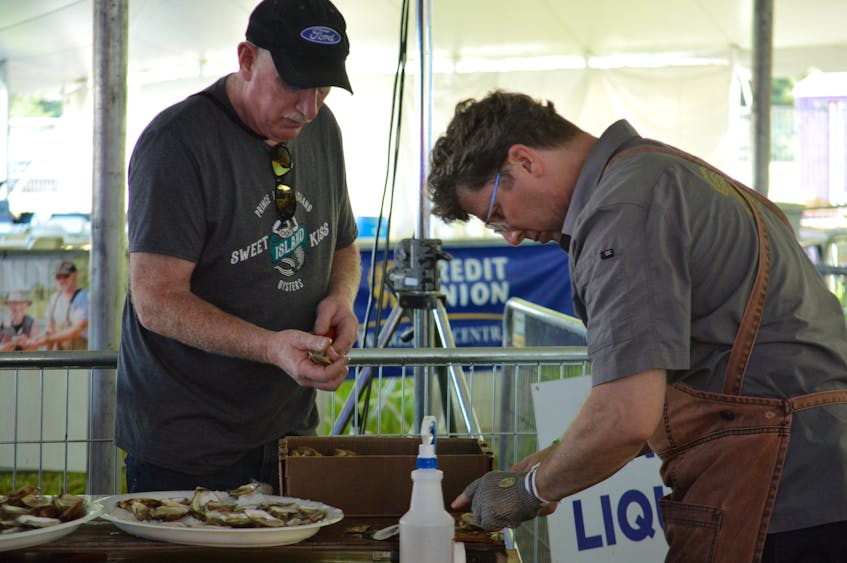 Dave Mullins, left, and Patrick McMurray shuck a few oysters for festival goers at the 2021 Tyne Valley Oyster Festival.  - Saltwire network