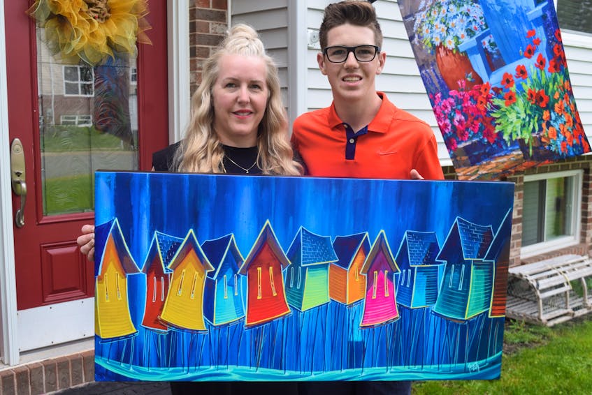 Jax Gaudet and his mother, Lana McMackin, hold up a painting by Adam Young of Young Studios that will be auctioned online for Jax's Make-A-Wish fundraiser. Before this, he has an even bigger fundraiser - VIP weekend passes for County Rocks the Hub and Rock the Hub festivals.