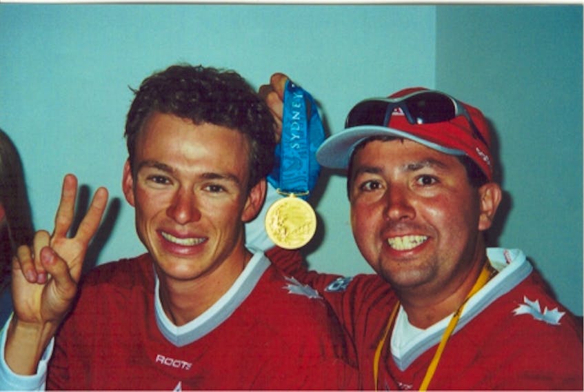 Canada's Simon Whitfield, left, poses with his coach, Barrie Shepley, and the gold medal he won in triathlon's Olympic debut at the 2000 Sydney Games.