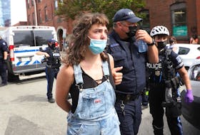 A woman is arrested during protests in downtown Halifax against the removel of temporary housing shelters on Wednesday, Aug. 18, 2021.