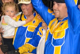 Trainer Patrick Shepherd raises the trophy while celebrating with his brother and driver Robert Shepherd and his daughter Taylor in the winner’s circle in the early minutes of Aug. 22.  Smooth Lou won the 62nd edition of The Guardian Gold Cup and Saucer at Red Shores Racetrack and Casino at the Charlottetown Driving Park in 1:51.1.