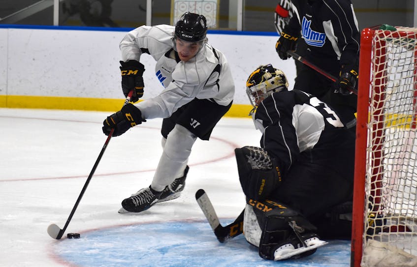 Team White forward Kiefer Lyons prepares to make a move in-tight at the top of the crease as Team Black goaltender Nicolas Ruccia watches the puck closely during Cape Breton Eagles black and white intrasquad game at Miners Forum in Glace Bay on Monday. Team Black won the game 7-2. - Jeremy  Fraser