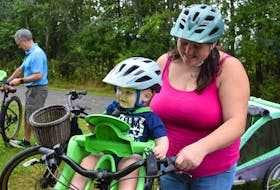 Marcus Scott enjoyed some of the attention while trying out an infant carrier with mom Kelsey Rogers watching. There is a variety of equipment that can be used to get the whole family cycling confidently. 