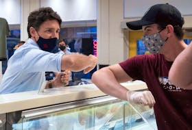  Justin Trudeau, elbow taps with a staff member at the Cows Creamery in Charlottetown, Prince Edward Island, during campaigning Aug. 22, 2021.