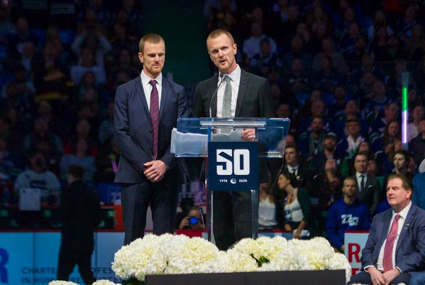  Henrik Sedin speaks at the podium with brother Daniel (left), a seated Canucks general manager Jim Benning (right) and a capacity crowd at Rogers Arena, as Vancouver celebrated a tribute night to the retired twins on Feb. 12, 2020. Daniel says he has a lot of appreciation for how hard Benning works the phones in his job.