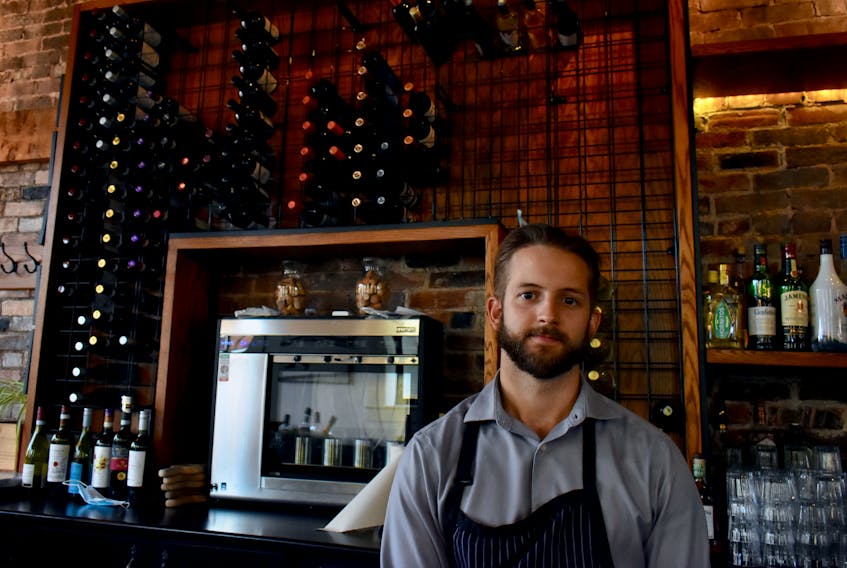 Daniel Good, manager at Piatto Pizzeria and Enoteca in Charlottetown, stands in front of a dwindling supply of wines. Though the restaurant hasn't been keeping as much stock on hand since the pandemic started, in the last month shortages have been keeping shelves even more bare.