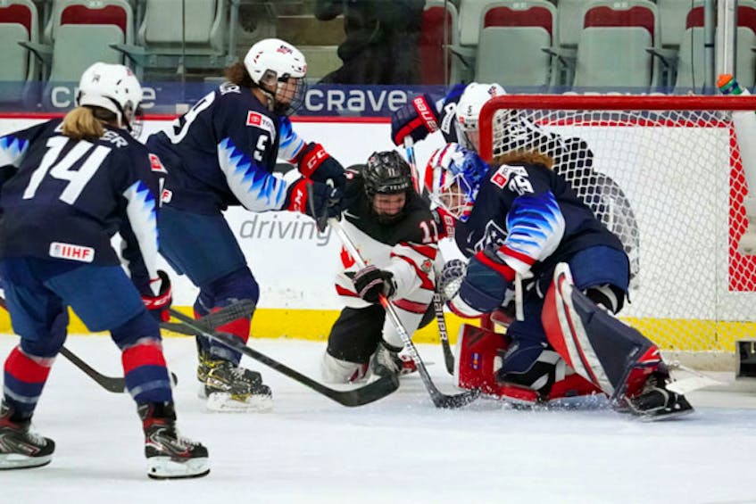 Halifax’s Jill Saulnier fights for the puck in front of U.S. netminder Nicole Hensley during their game in the preliminary round of the IIHF women’s world championship in Calgary on Thursday, Aug. 26, 2021 - IIHF