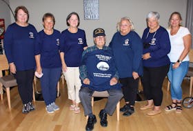 The nieces of Lovira Wright Leggett Jr. with Gus Etchegary: (from left) Jo Pardue, Jeanie Sasser, Sarah Steele, Gus Etchegary, Sallie Smith, Sue Hagan and Betty Landon. The back of their shirts read, "Lovira Wright Legett Jr. Survivor of USS Truxtun, February 18, 1942. Thank you to the citizens of St. Lawrence for allowing our uncle to come home!" Landon gifted her shirt to Etchegary.