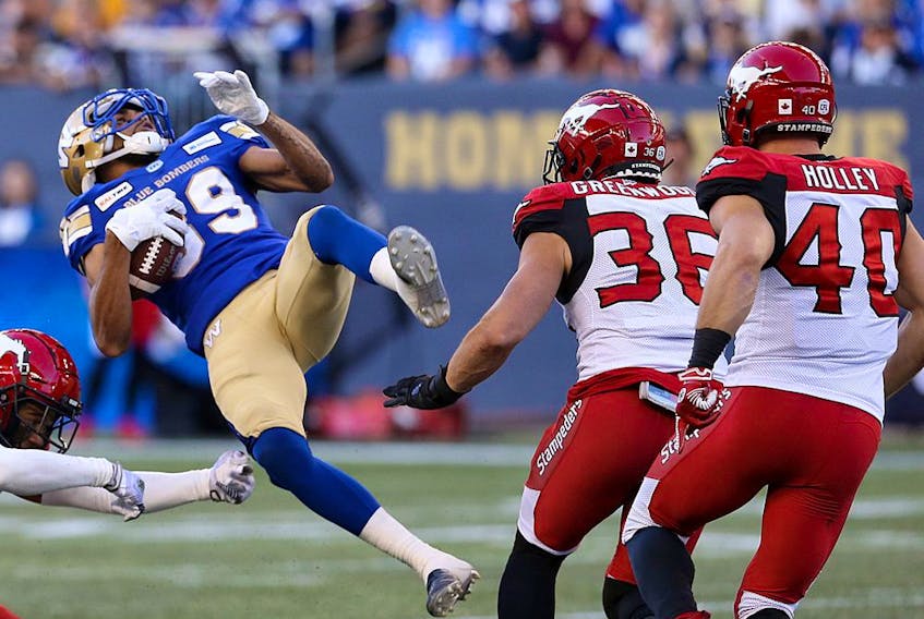 Winnipeg Blue Bombers receiver Kenny Lawler (centre) is spun around by Calgary Stampeders defensive back Royce Metchie (left) during CFL action in Winnipeg on Thurs., Aug. 8, 2019. Kevin King/Winnipeg Sun/Postmedia Network ORG XMIT: POS1908082117381746