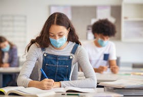 High school students take notes while wearing face masks in the classroom.