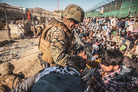 A U.S. marine assists at an evacuation control checkpoint during an evacuation at Hamid Karzai International Airport on Aug. 26 in Kabul, Afghanistan. U.S. Marine Corps/Staff Sgt. Victor Mancilla/Handout via REUTERS