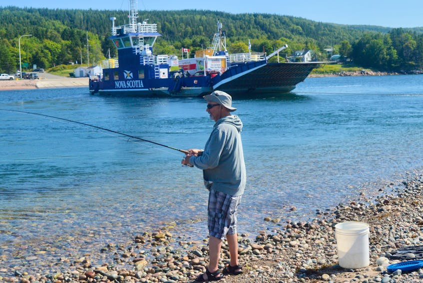 John Alexander was in his happy place one afternoon last week while fishing for mackerel at the mouth of St. Ann's Bay. Meanwhile, the Torquil MacLean ferry is seen in the background on its continuous run between the Englishtown and Jersey Cove terminals. Recent warm temperatures have meant longer lineups at the provincially-run ferry that serves as a shortcut for travellers heading to or from the Cape Breton Highlands. DAVID JALA • CAPE BRETON POST