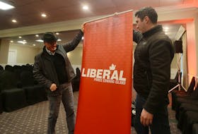 Liberal party members set up a banner at a campaign event.