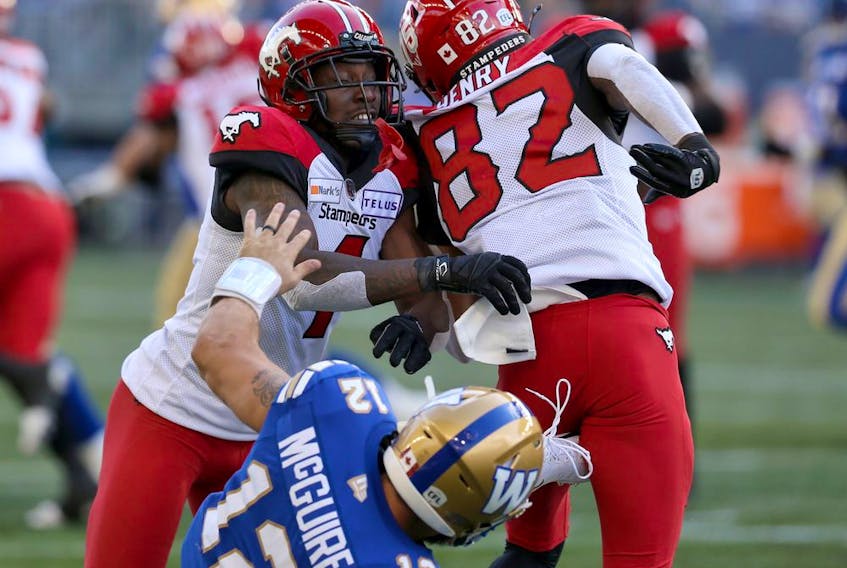  Winnipeg Blue Bombers backup QB Sean McGuire (bottom) gets the worst of it as a pair of Calgary Stampeders during CFL action at IG Field in Winnipeg on Sun., Aug. 29, 2021.