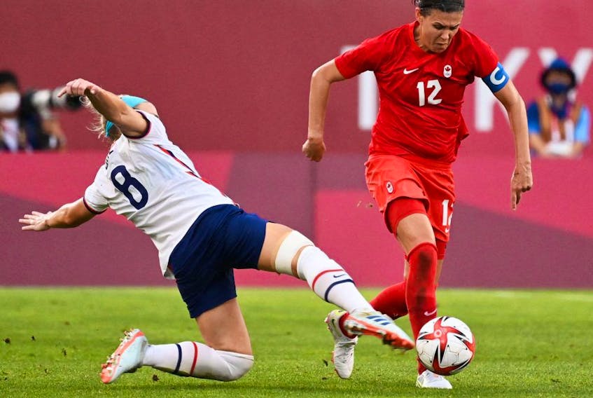  USA’s midfielder Julie Ertz (L) tackles Canada’s forward Christine Sinclair during the Tokyo 2020 Olympic Games women’s semi-final football match between the United States and Canada at Ibaraki Kashima Stadium in Kashima on August 2, 2021.