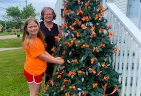 Cathy Halliday and her grandniece Melissa Sherwood-Gerow stand next to a tree with orange ribbons decorated as a tribute to our nation’s Indigenous communities impacted by the recent discoveries of graves at former residential school sites. CONTRIBUTED
