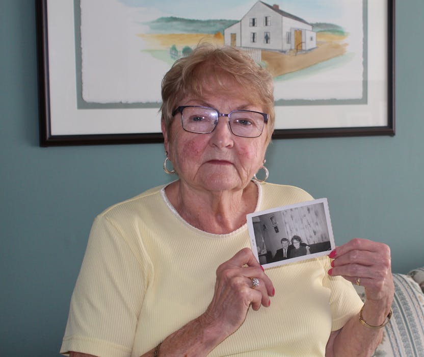 Helen Boland holds a photo of her and her brother, Frank Brennan. In the background is a painting Boland's husband, Gerry, did of the Brennan family farmhouse. — Barb Sweet