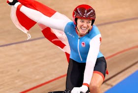 Kelsey Mitchell of Canada celebrates with a national flag after winning gold in the cycling sprint at the Izu Velodrome in Shizuoka, Japan, on Aug. 8, 2021.