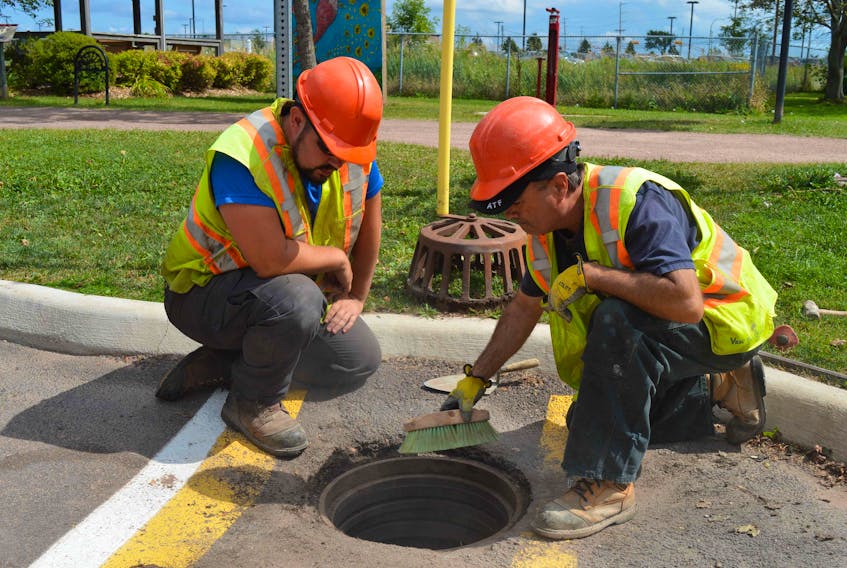Brent MacRae, right, chief of Charlottetown’s public works catch basin crew, and Mark Lee, a member of the public works crew, clean around a catch basin adjacent to the Joe Ghiz Park on Kent Street on Sept. 1. Remnants of hurricane Ida are expected to impact P.E.I. between Sept. 2-4.