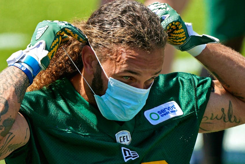 Defensive halfback Aaron Grymes puts on a face mask during Edmonton Elks training camp at Commonwealth Stadium on July 12, 2021. The team returned to the field Wednesday after serving a 10-day quarantine after 13 players tested positive for COVID-19.