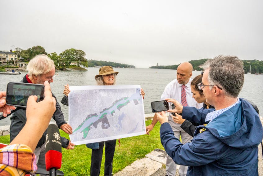 Leslie Shaw, centre, with help from Allan Shaw, left, and Halifax MP Andy Fillmore, shows a map of the Northwest Arm in Halifax to reporters at Horseshoe Island Park on Friday, Sept. 10, 2021. The green sections on the map show the potential areas which could be infilled.