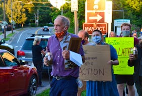 Holding a candle lantern and an armful of petitions, Alan Warner leads a group of climate crisis demonstrators down Wolfville’s Main Street. KIRK STARRATT