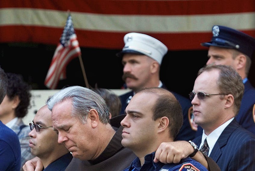 Members of the New York Fire Department embrace at the funeral of Father Mychal Judge, a fire department chaplain who died on duty on September 11, 2001 as the World Trade Center towers collapsed.