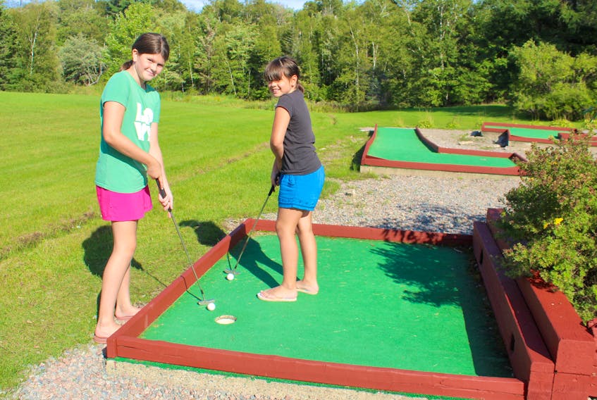Maddie Maloney, 11, left, and Alex Maloney, 9, prepare to putt while playing mini-golf at the Red Barn Gift Shop and Restaurant in Nyanza, Victoria County, on Monday. The Sydney sisters were taking a road trip with their grandmother Phyllis Crocker and great-aunts Jenny Rideout and Gladys Everard, who were visiting from Newfoundland. Chris Connors • Cape Breton Post 