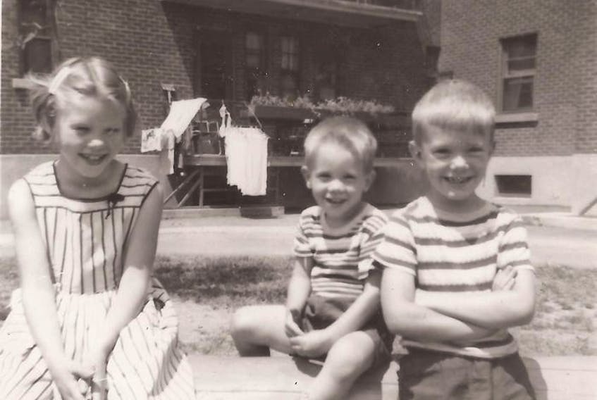  Snapshots from 1955, at Benny Farm in N.D.G.: Top, Andrew Caddell on skates for the first time outside the housing complex; and in the block yard, beside siblings Susan and Ian, left, with the family’s second-floor apartment behind them. Photo courtesy Caddell family.