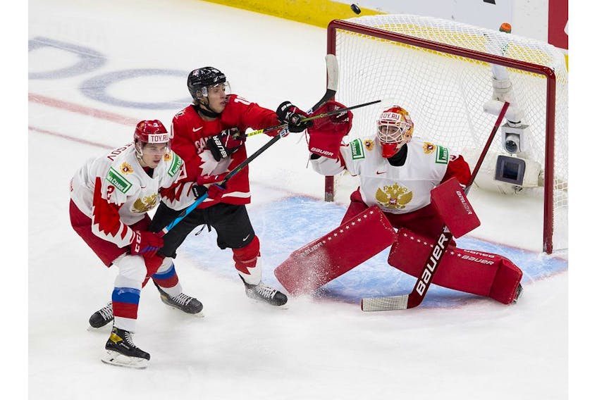 Canada's Dylan Holloway (10) reaches for the puck as does Russia's Yaroslav Askarov (1) and Yan Kuznetsov (2) during first period IIHF World Junior Hockey Championship semifinal action on Monday, Jan. 4, 2021 in Edmonton. 