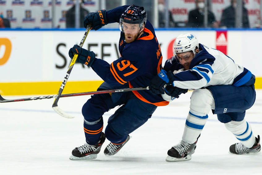 Edmonton Oilers captain Connor McDavid (97) battles Winnipeg Jets’ Dylan DeMelo (2) during the first period of their NHL North Division playoff series at Rogers Place in Edmonton on Wednesday, May 19, 2021.