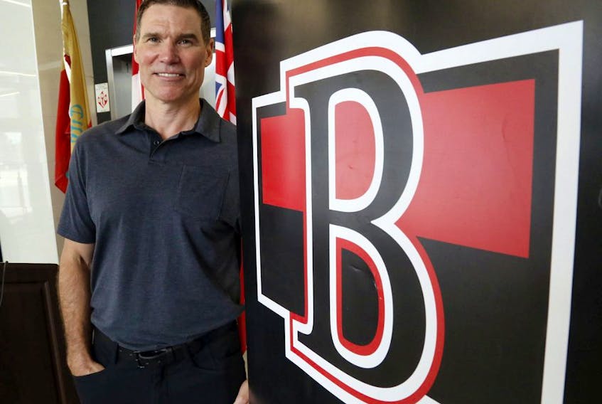 File photo/ The Belleville Senators' head coach, Troy Mann, stands next to the team's logo Tuesday, July 27, 2021 in Belleville.