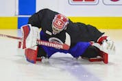 Montreal Canadiens goalie Carey Price stretches on the ice under the supervision of a member of the team's training staff at the Bell Sports Complex in Brossard on Thursday, Sept. 16, 2021.
