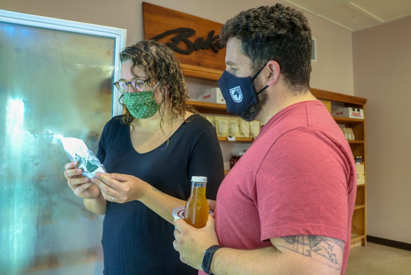 Katie MacLeod, left, and Joel Inglis, right, look at some product in one of the fridges at the Food Hub store on its opening day. JESSICA SMITH/CAPE BRETON POST