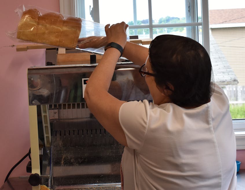Beverley King slices bread to fill the shelves at Just Like Sisters Bakery and Sweet Shop in Heart's Content. - Kyle Curtis