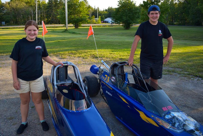 Jacey Pozzebon, left, and her brother Gavin Pozzebon stand near their respective dragsters in the driveway of the family’s home in Gardiner Mines on Wednesday. The two will compete in the junior dragsters division this weekend at Cape Breton Dragway in Sydney. JEREMY FRASER • CAPE BRETON POST