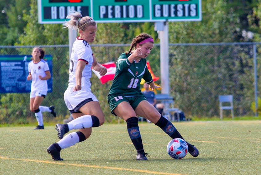Victoria Miller of the Cape Breton Capers, right, protects the ball as she's pressured by  Jesse Bellamy of the New Brunswick Reds during Atlantic University Sport women's soccer action at Willie O’Ree Place Complex in Fredericton. Cape Breton won the game 5-0. PHOTO CONTRIBUTED/JAMES WEST, UNB ATHLETICS.