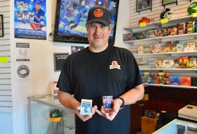 Light The Lamp Sports Card shop owner Gordon Woodill displays some of the wares available at his new business that is located on Charlotte Street in Sydney. DAVID JALA/CAPE BRETON POST