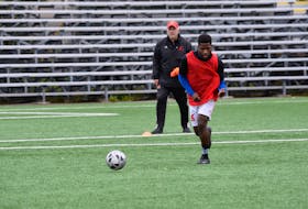 As head coach Jake Stanford (left) looks on, Memorial Sea-Hawks first-year soccer player Emmanuel Dolo moves the ball down the field during a recent practice at King George V Park in St. John's.