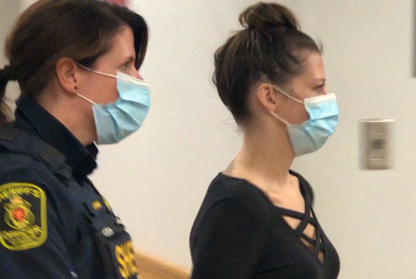 A sheriff escorts Katie Marie Tucker into a provincial courtroom in St. John's, where she was officially charged with nine offences related to illegal drugs and weapons as part of RCMP Project Barnacle.