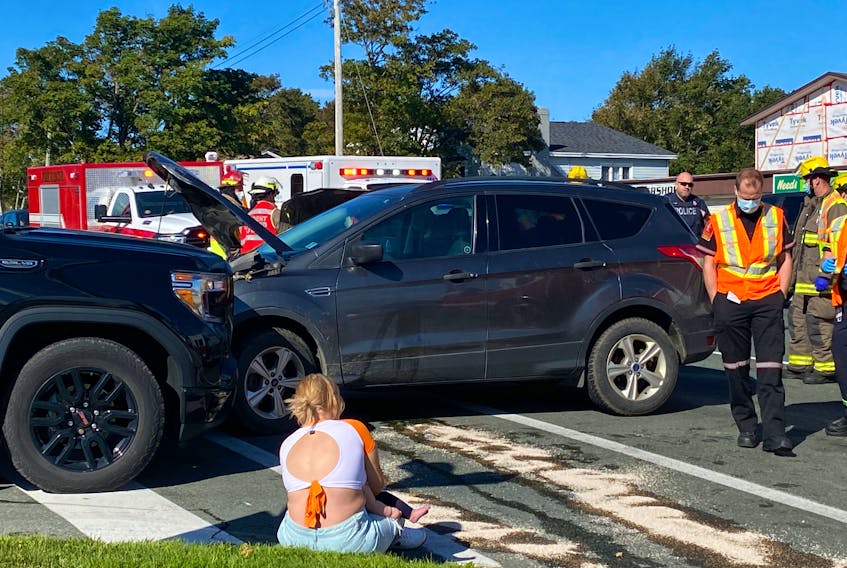 A woman involved in a three-car collision in Mount Pearl on Thursday, Sept. 23, 2021, sits on the curb with her infant child.