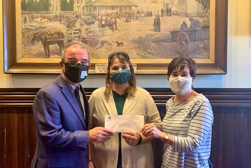 Mayor Philip Brown presents gift certificates to Judy Skerry (middle) and Carol Smith, who accepted the prize on behalf of the volunteers who worked in the gardens at the Holy Redeemer Catholic Parish Church--the winner of the 2021 Mayor’s Award in the city's Make Our Hometown Beautiful program.