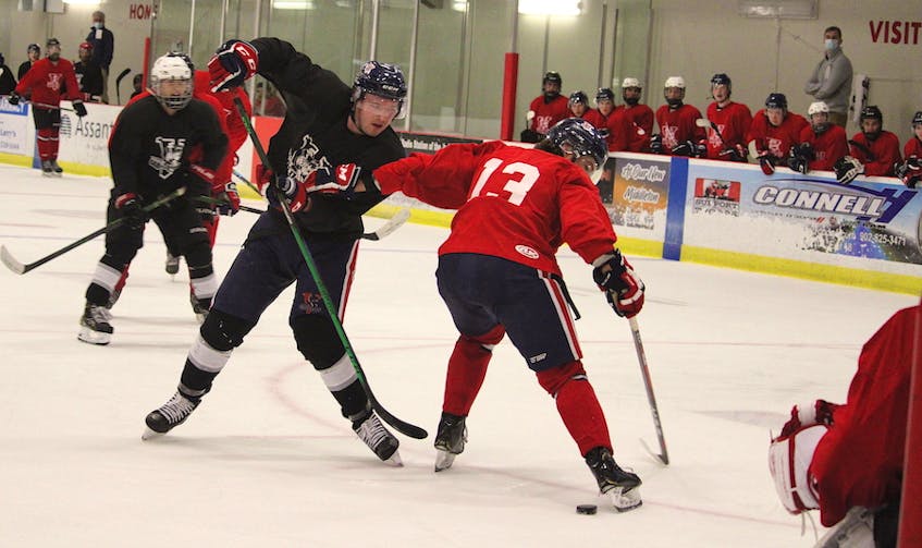 Team Black forward Aaron Brown, centre, tries to get the puck through Team Red blue-liner Keigan Casey. - Jason Malloy