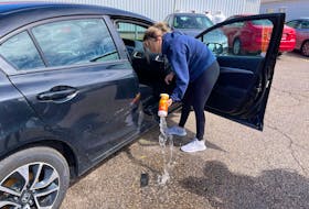 Kaleigh Foley, a first-year student at Holland College in Charlottetown, scoops water out of her car on Sept. 3 after heavy rain from the remnants of hurricane Ida left it partially under water in the Glendenning Hall parking lot the day before.