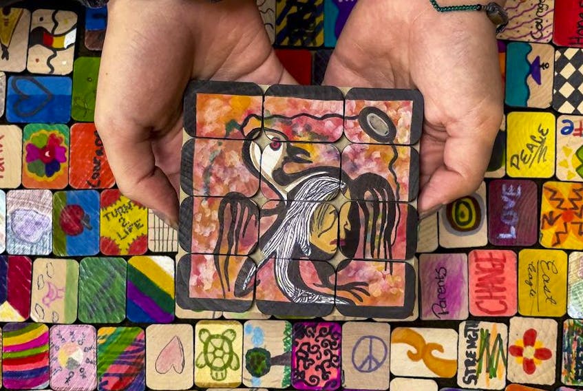  The hands of 17 year old Azia Seitcher, a member of the Nuu-Chah-Nulth First Nation from Vancouver Island, holds tiles painted by children that were being laid out in a memory labyrinth in preparation for September 30, 2021.