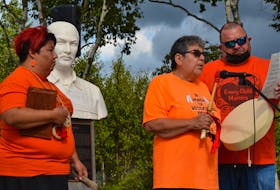 Candace Sylliboy, left, the granddaughter of a residential school survivor, looks on as Shubenacadie Indian Residential School survivor, Shirley Christmas, sings a song she wrote for the children who never made it home from residential school during a ceremony marking the National Day for Truth and Reconciliation in Membertou. Coun. Paul MacDonald, right, holds up the lyrics she wrote. ARDELLE REYNOLDS/CAPE BRETON POST