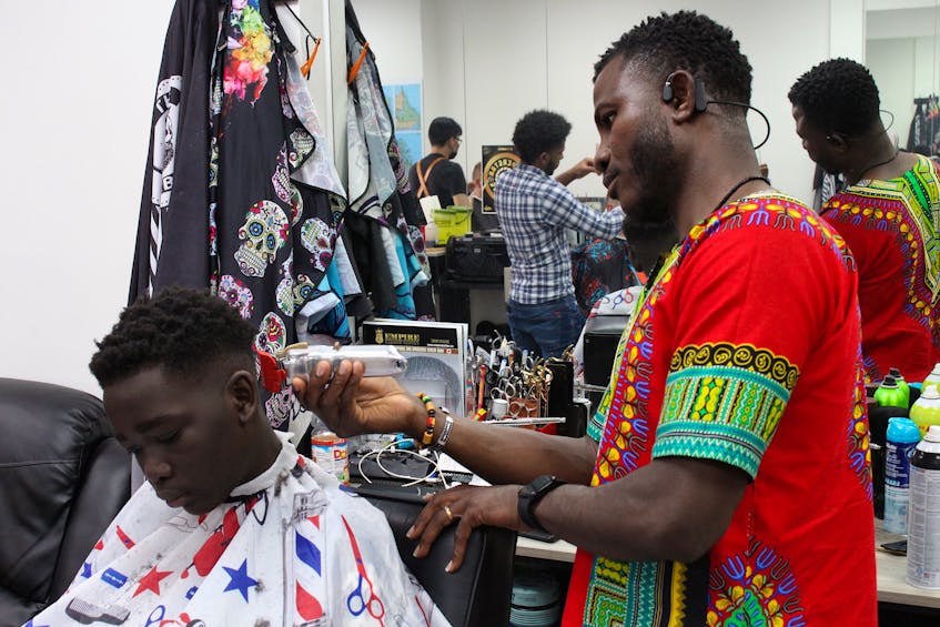 Yaw Antwi-Adjei (right) is co-owner of 1949 Barbershop, which has two locations in St. John's. One is in the Torbay Road Mall and the newest location is in the Villiage Shopping Centre. Sitting in the chair is Noaman Gartour, who says he only trusts Antwi-Adjei with his hair. - Andrew Waterman/The Telegram