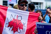  A man holds an upside-down Canadian flag in a protest against vaccination, during Canada’s Liberal Prime Minister Justin Trudeau’s election campaign tour stop in Brantford, Ontario, Canada September 6, 2021.