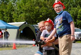 Jessica Gaetz helps Ryer Pinch, 3, and Jadam Gaetz, 9, practice using a firefighter’s hose during an emergency preparedness day at the Vaughan fire hall Aug. 28.